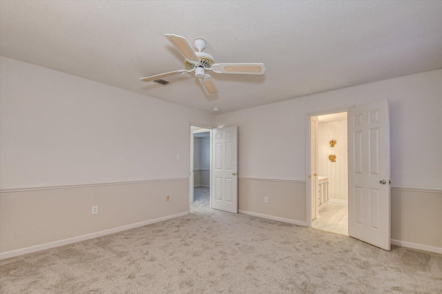 unfurnished bedroom featuring visible vents, ensuite bathroom, a ceiling fan, carpet, and baseboards