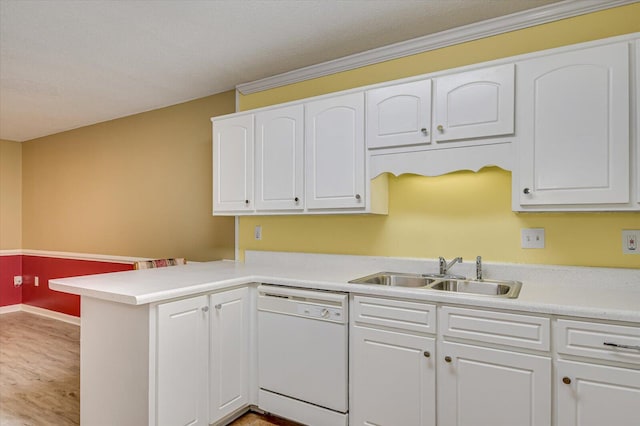 kitchen featuring light countertops, a peninsula, white dishwasher, white cabinets, and a sink