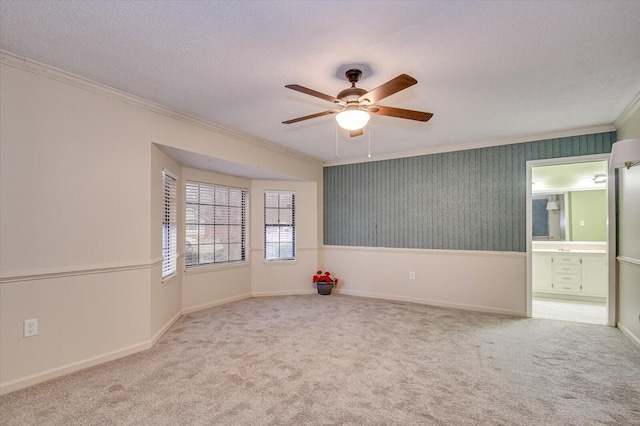 unfurnished room with baseboards, ceiling fan, carpet, ornamental molding, and a textured ceiling