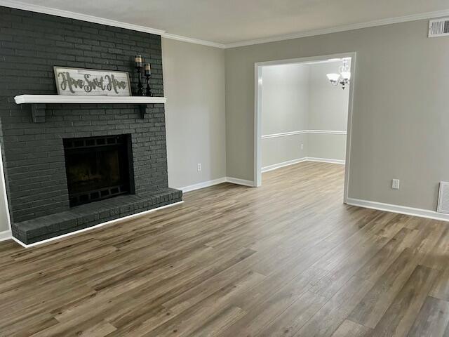 141 Glenora Dr, Martinez, GA 30907 - unfurnished living room with ornamental molding, baseboards, a chandelier, and wood finished floors