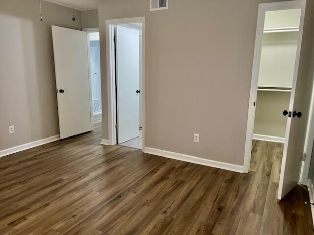 141 Glenora Dr, Martinez, GA 30907 - unfurnished bedroom with a closet, visible vents, a walk in closet, baseboards, and dark wood-style floors