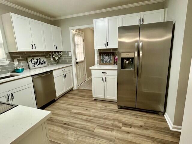 141 Glenora Dr, Martinez, GA 30907 - kitchen with ornamental molding, white cabinetry, light countertops, stainless steel appliances, and light wood finished floors