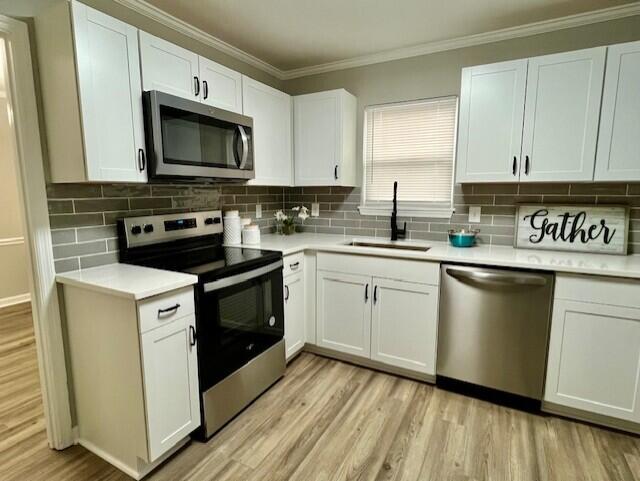 141 Glenora Dr, Martinez, GA 30907 - kitchen with light wood-type flooring, ornamental molding, appliances with stainless steel finishes, light countertops, and a sink