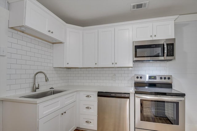 kitchen featuring white cabinets, stainless steel appliances, tasteful backsplash, and sink