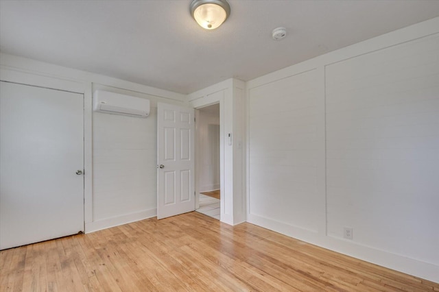 unfurnished bedroom with an AC wall unit and hardwood / wood-style floors