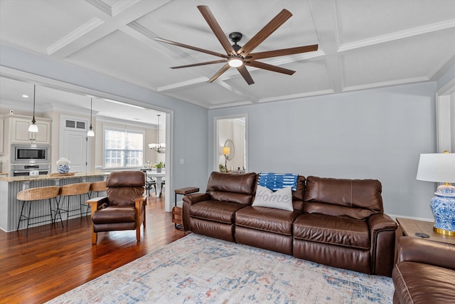 living room featuring dark wood-type flooring, coffered ceiling, crown molding, beamed ceiling, and ceiling fan with notable chandelier