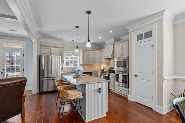 kitchen featuring pendant lighting, premium range hood, stainless steel appliances, a center island, and light stone countertops