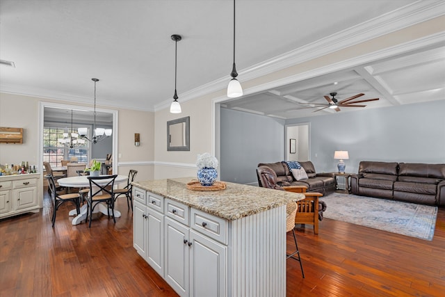 kitchen with coffered ceiling, white cabinetry, hanging light fixtures, dark hardwood / wood-style flooring, and a kitchen island