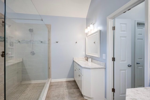 bathroom with tiled shower, vanity, tile patterned floors, and baseboards