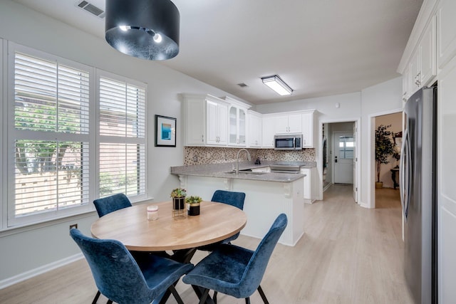 dining space with healthy amount of natural light, light wood-style flooring, and baseboards
