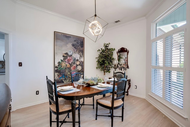 dining room featuring light wood-type flooring, plenty of natural light, ornamental molding, and a chandelier