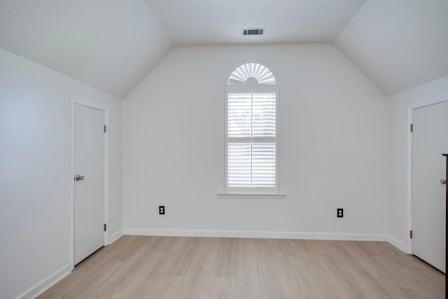 additional living space with light wood finished floors, healthy amount of natural light, vaulted ceiling, and baseboards