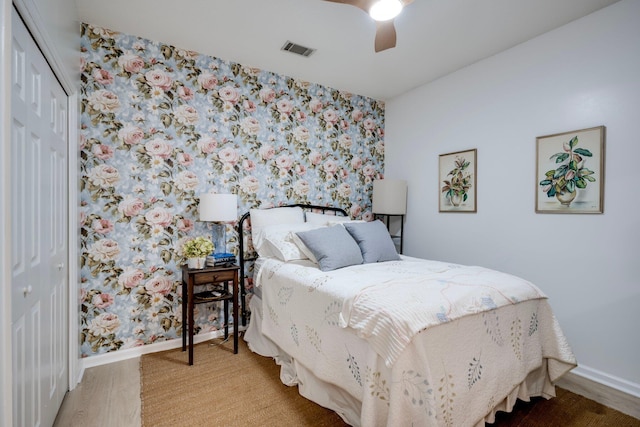 bedroom with wallpapered walls, a closet, baseboards, wood finished floors, and ceiling fan