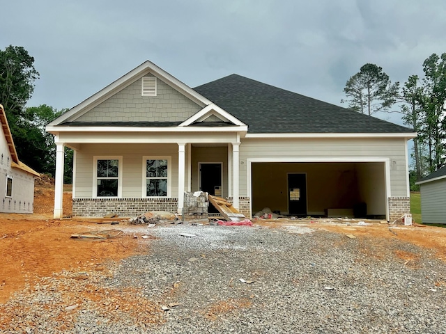 craftsman-style home with an attached garage, a shingled roof, a porch, and driveway
