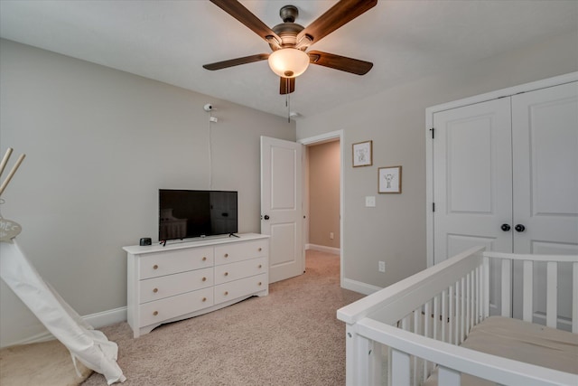 bedroom featuring ceiling fan, light carpet, baseboards, and a closet