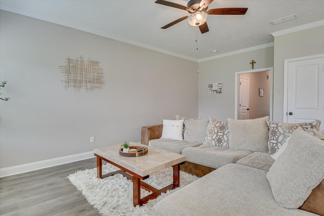 living room with visible vents, crown molding, wood finished floors, baseboards, and a ceiling fan