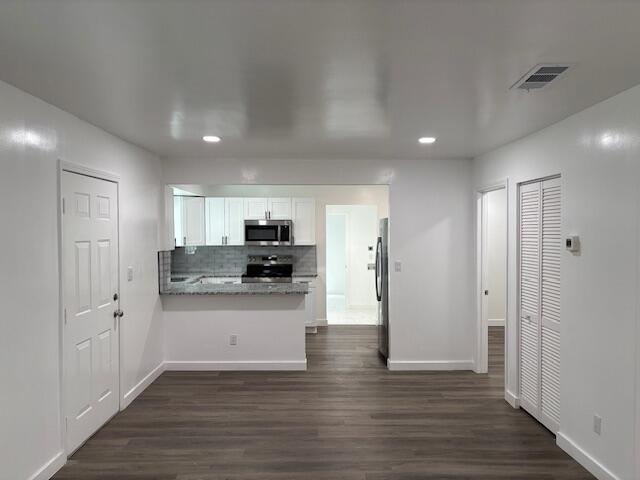 875 Earle St, Thomson, GA 30824 - kitchen with appliances with stainless steel finishes, a peninsula, white cabinets, baseboards, and dark wood-style floors