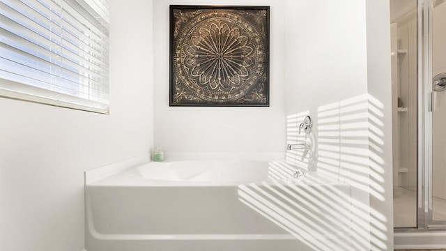 bathroom featuring a garden tub and a shower stall