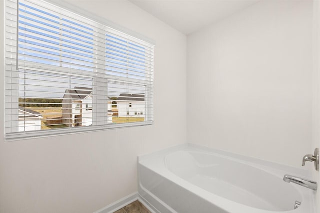 full bathroom featuring a bath and baseboards