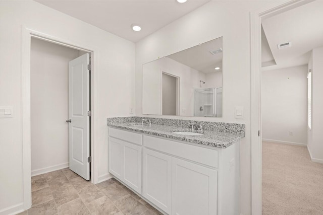 full bathroom with double vanity, a sink, visible vents, and baseboards