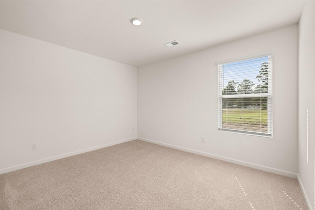 spare room featuring light carpet, visible vents, and baseboards