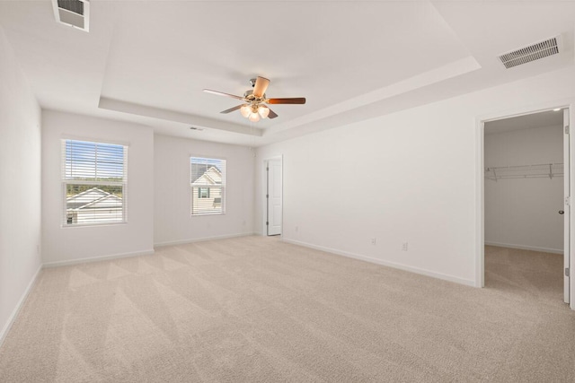 spare room featuring a tray ceiling, visible vents, and baseboards