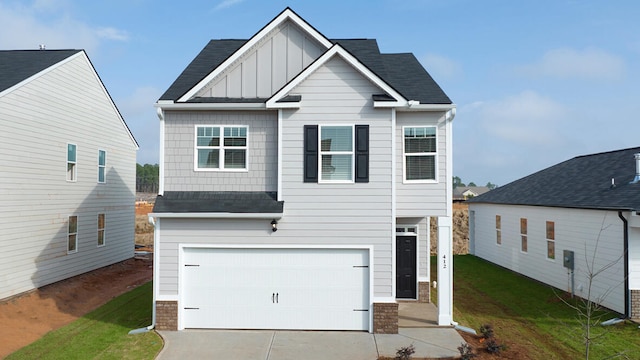 view of front facade featuring a shingled roof, concrete driveway, an attached garage, a front lawn, and board and batten siding