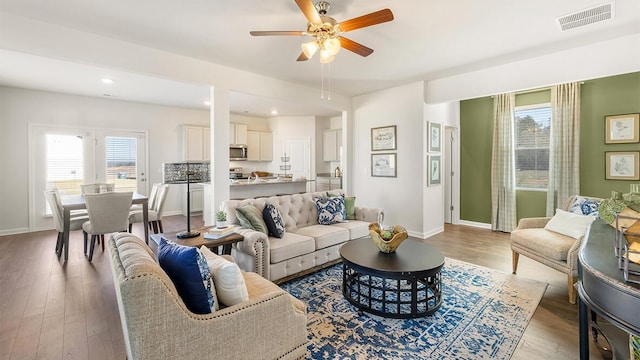 living area with a healthy amount of sunlight, light wood-style flooring, visible vents, and baseboards