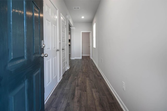 hall featuring baseboards, visible vents, and dark wood-style flooring