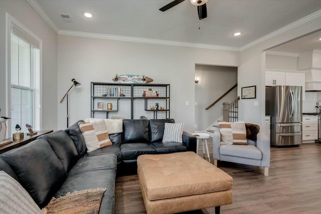 living area featuring visible vents, ceiling fan, stairway, dark wood-type flooring, and crown molding