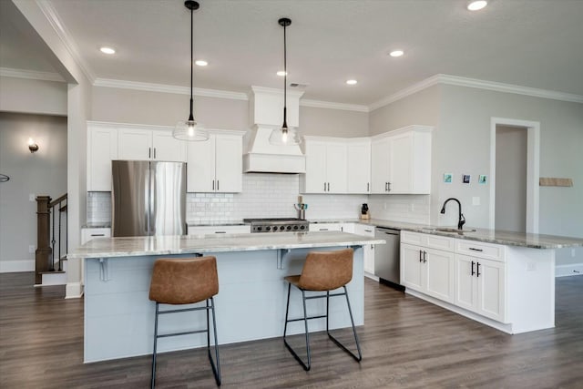 kitchen with stainless steel appliances, a sink, decorative light fixtures, and white cabinets