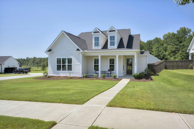 cape cod home featuring covered porch, a front lawn, a shingled roof, and fence