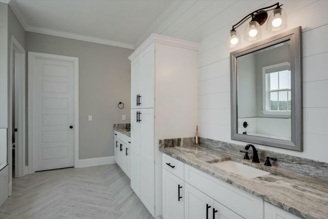 full bath with a sink, baseboards, two vanities, and crown molding