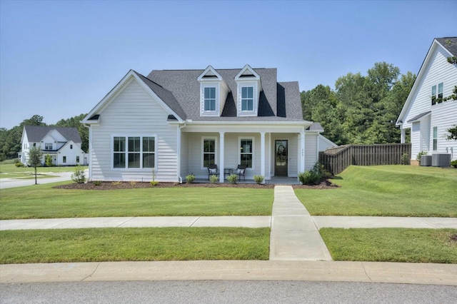 view of front of house featuring roof with shingles, covered porch, fence, a front lawn, and central AC