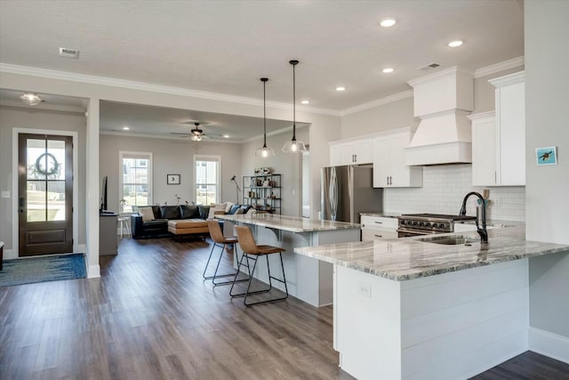 kitchen featuring light stone counters, stainless steel appliances, hanging light fixtures, open floor plan, and white cabinetry