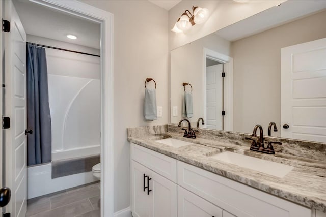 full bath featuring shower / bath combination with curtain, a sink, toilet, and double vanity