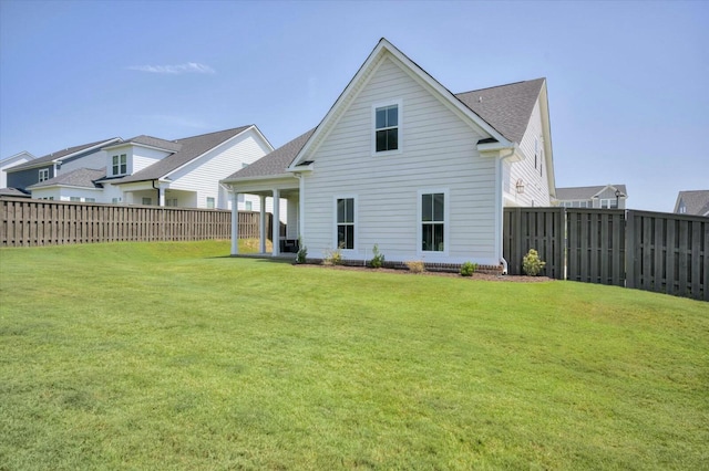 back of house with a lawn and a fenced backyard