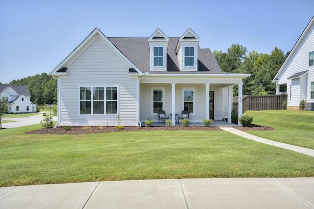 cape cod house featuring a shingled roof, fence, a front lawn, and a porch