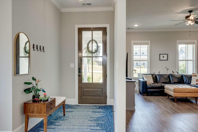 entryway with ornamental molding, visible vents, baseboards, and wood finished floors