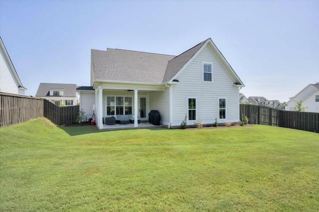 rear view of house with a shingled roof, a lawn, a patio area, and a fenced backyard