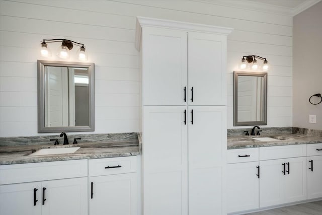 bathroom featuring crown molding, two vanities, and a sink