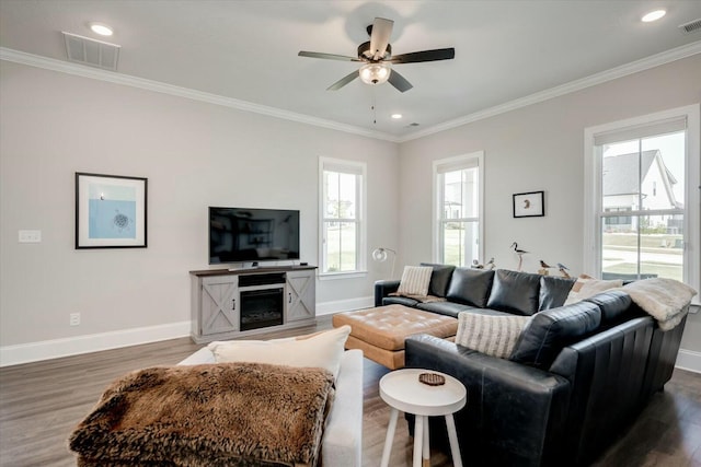 living room featuring dark wood-style flooring, crown molding, visible vents, a ceiling fan, and baseboards