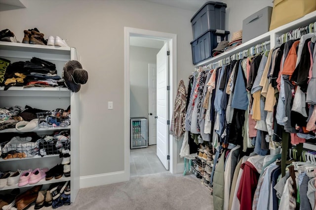 walk in closet featuring wine cooler and light colored carpet