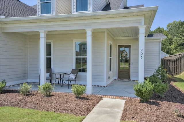 doorway to property with a shingled roof and a porch