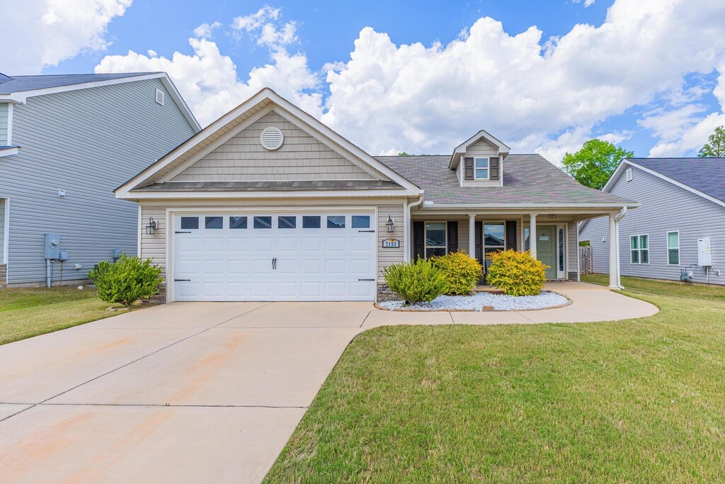 7193 Hanford Dr, Aiken, SC 29803 - view of front of home with a front yard, an attached garage, driveway, a porch, and stone siding