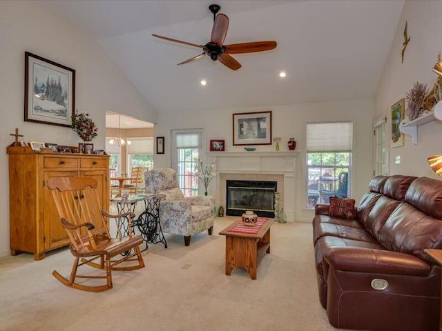 carpeted living room featuring ceiling fan with notable chandelier, a wealth of natural light, and vaulted ceiling