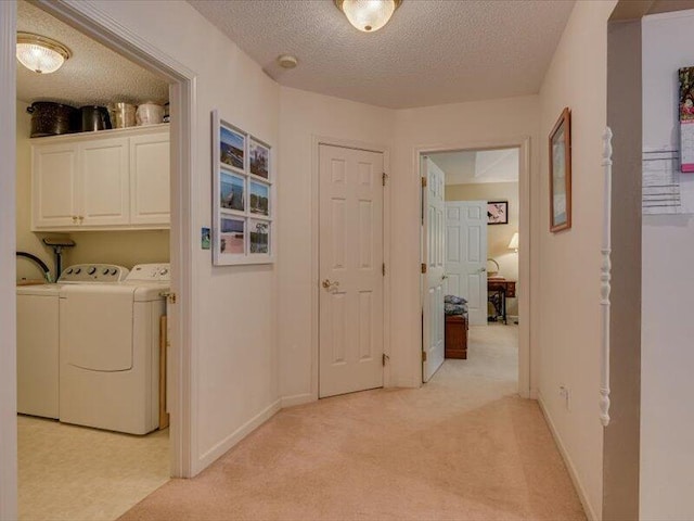 interior space featuring a textured ceiling, washer and dryer, cabinets, and light carpet