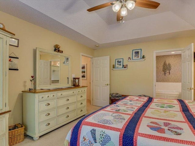 bedroom with a tray ceiling, ceiling fan, and ensuite bathroom