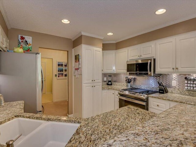 kitchen with white cabinets, decorative backsplash, stainless steel appliances, and light stone countertops