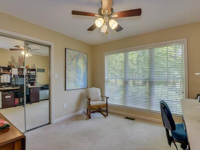 office area with light carpet, ceiling fan, and a healthy amount of sunlight